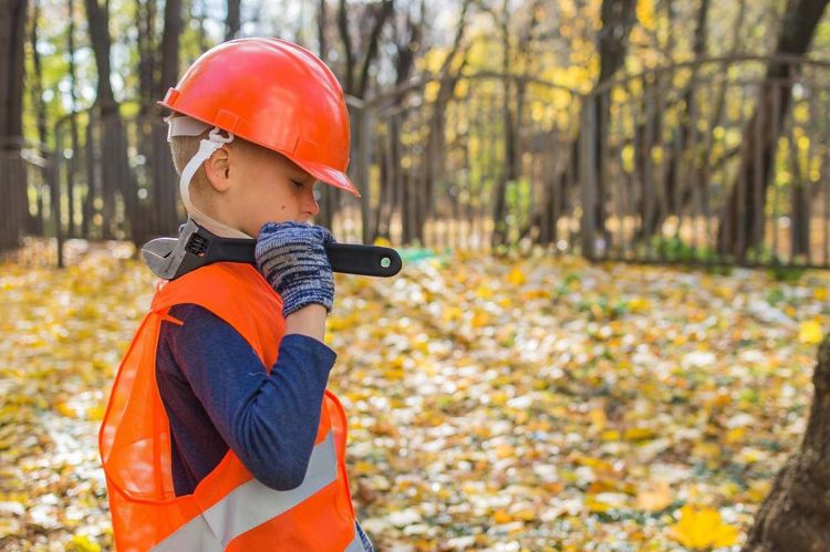 Child in high-vis and hard hat with wench in hand.